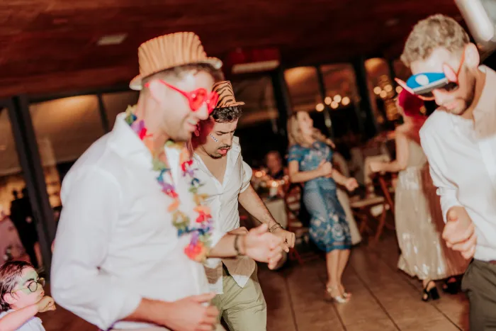 Convidados de chapéu, óculos e colares havaianos a dançar num casamento.