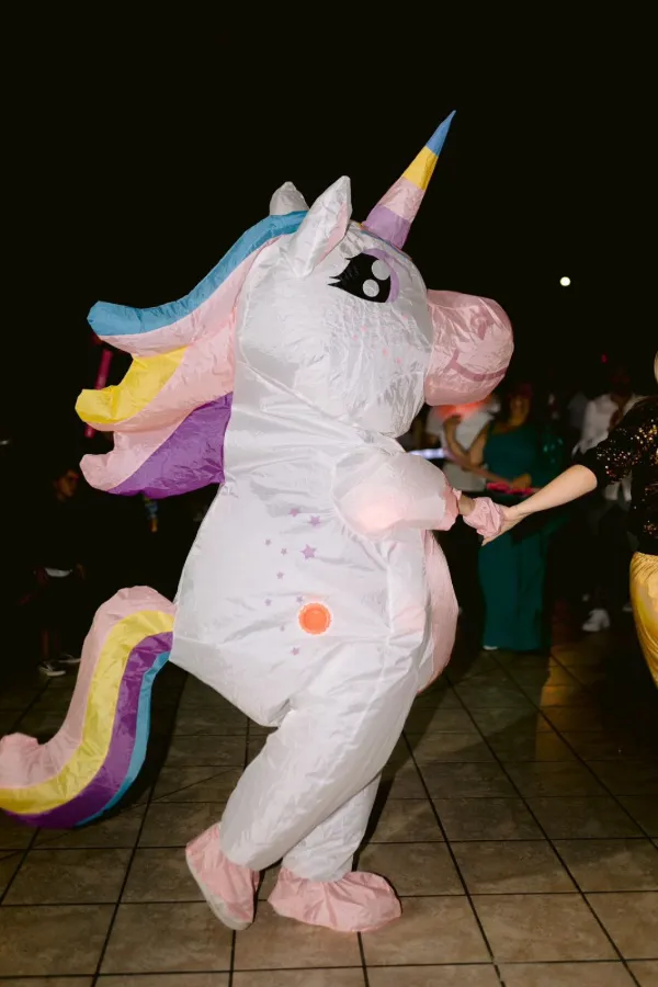 Mascote unicórnio insuflável a dançar com uma convidada.